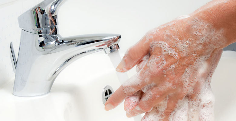 Eingeseifte Haende werden unter dem laufenden Wasserhahn gewaschen Eingeseifte Haende unter laufendem Wasser waschen